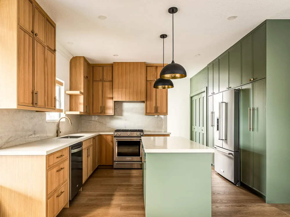 Remodeled Los Comancheros kitchen with oak cabinetry, black pendant lights and a green pantry wall.