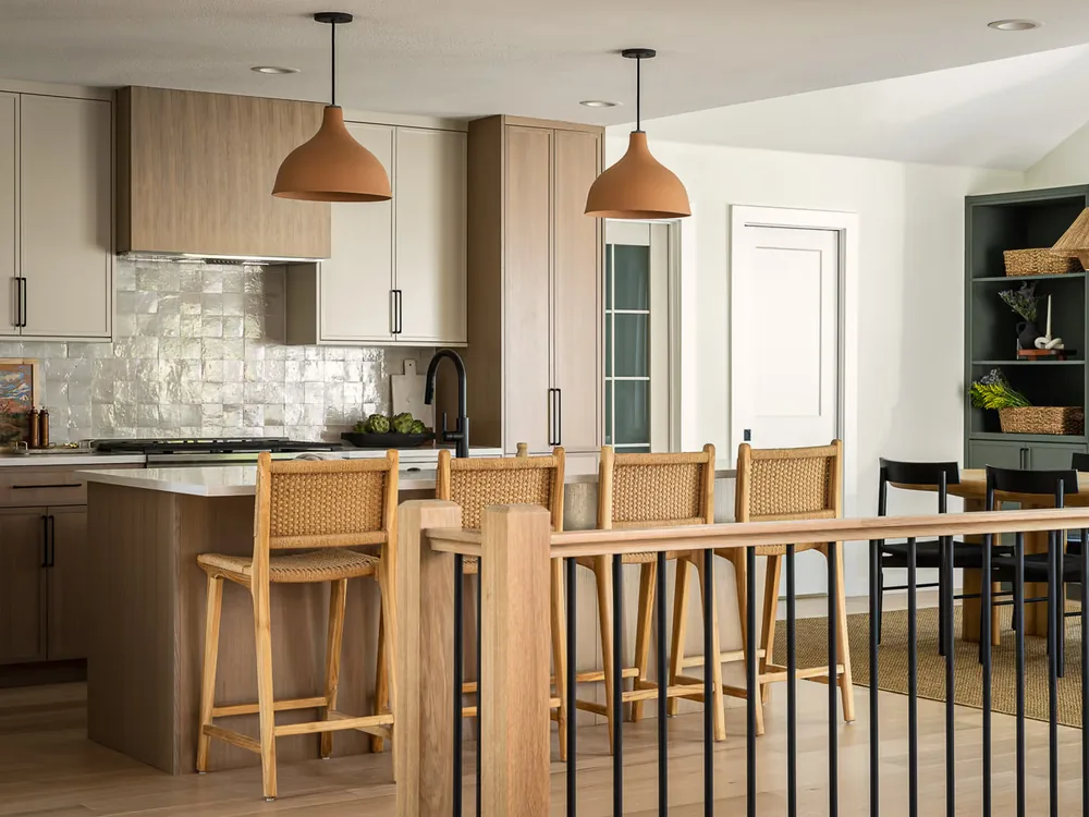 Remodeled Wagon Train kitchen and dining area with a pale wood island, woven bar stools and two pendant lights.